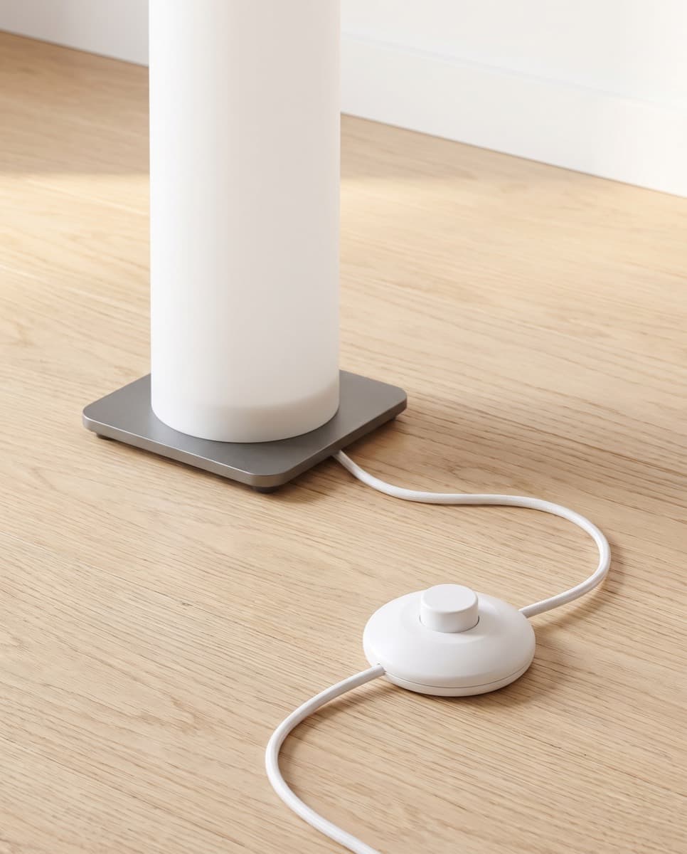 The weighted square metal base with the white cord and round foot switch on oak flooring